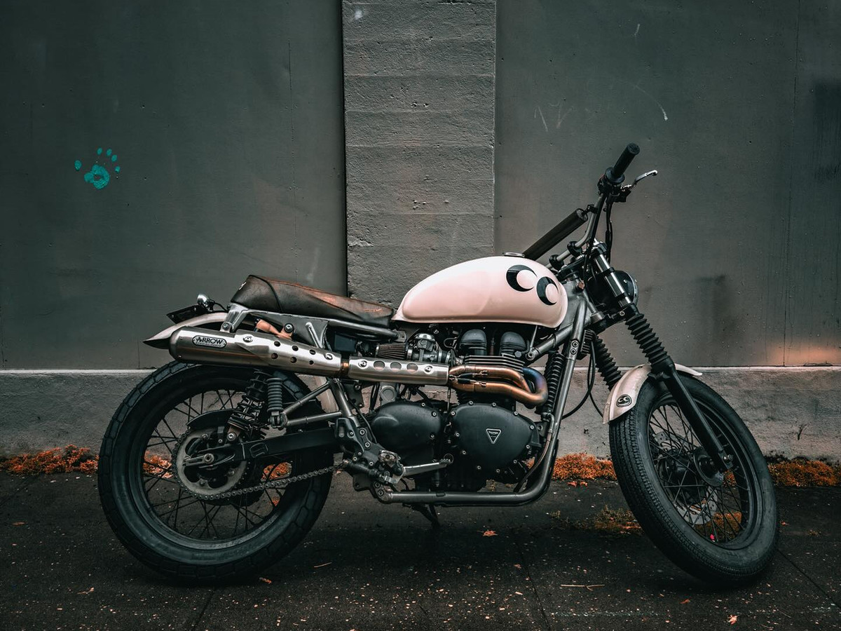 Pink-and-black Triumph scrambler custom build parked on a Portland sidewalk