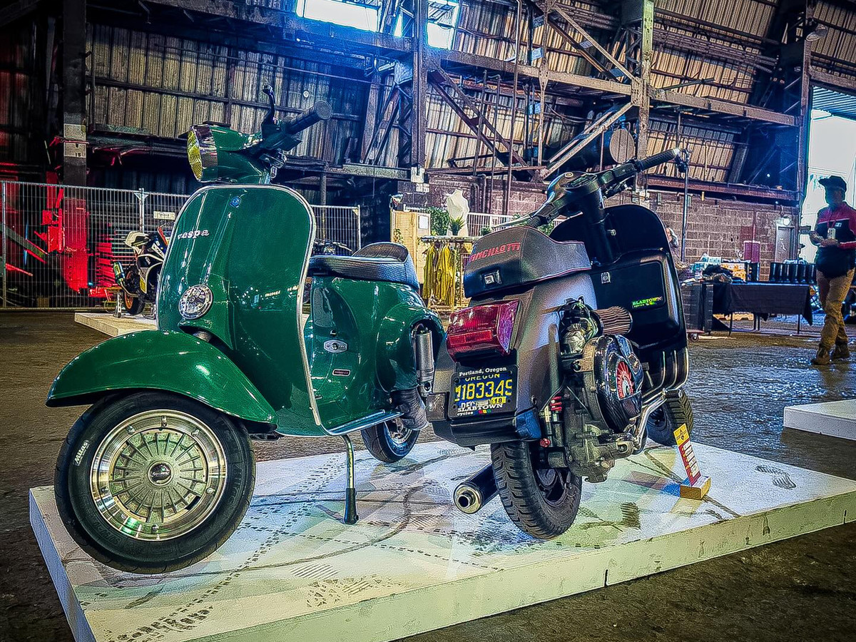 Green Vespa and silver Benelli scooter at a display